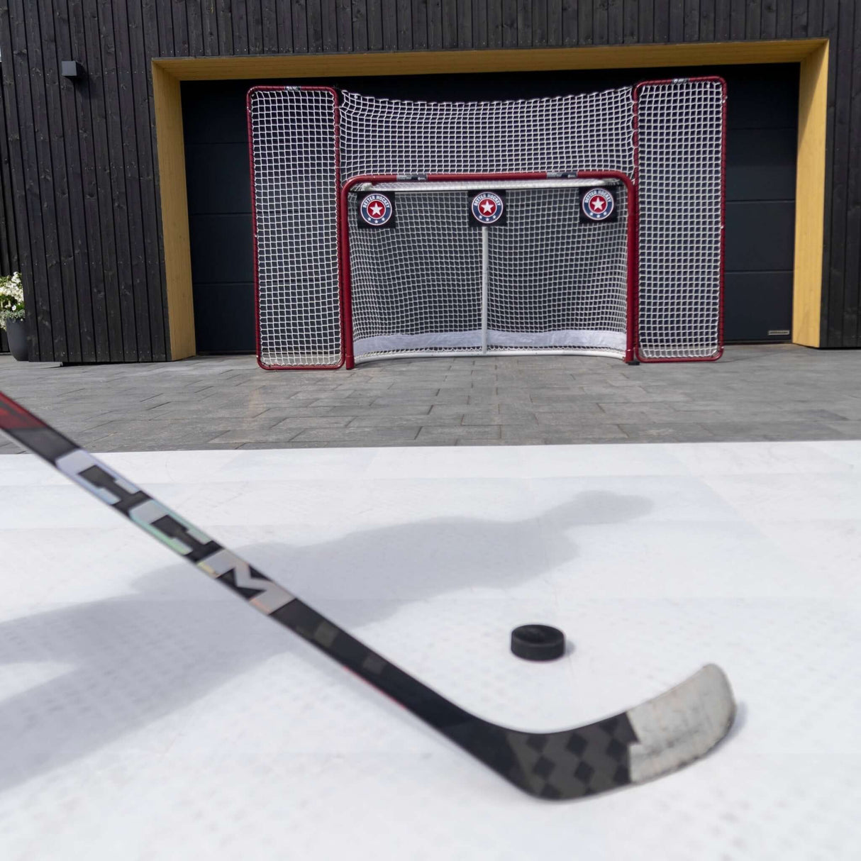 Hockeygolv med puck och klubba framför en målbur, perfekt för träning och skottramp med Plastis Extreme Flooring.
