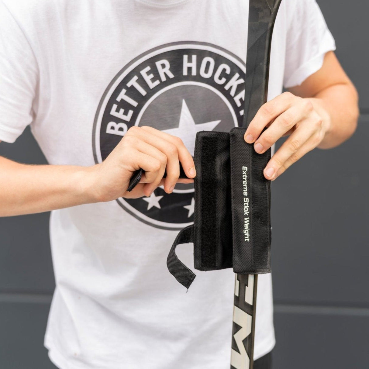 Person applying Extreme Hockey Pro Stick Weight to improve shooting and stickhandling skills with a hockey stick.