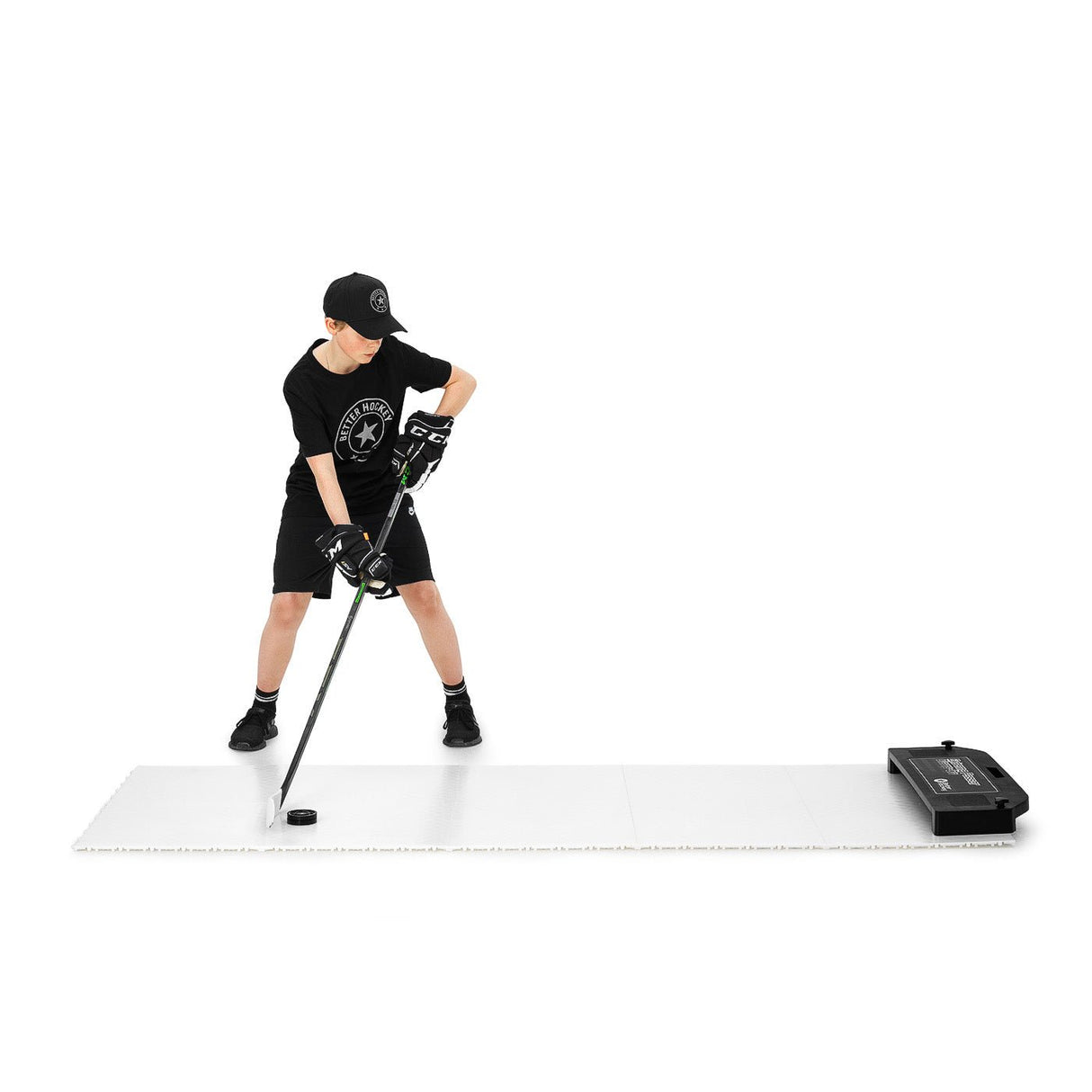 En pojke tränar hockey på Extreme Hockey Flooring Tiles med klubba och puck, klädd i sportoutfit. Ideal för torrlandsträning.