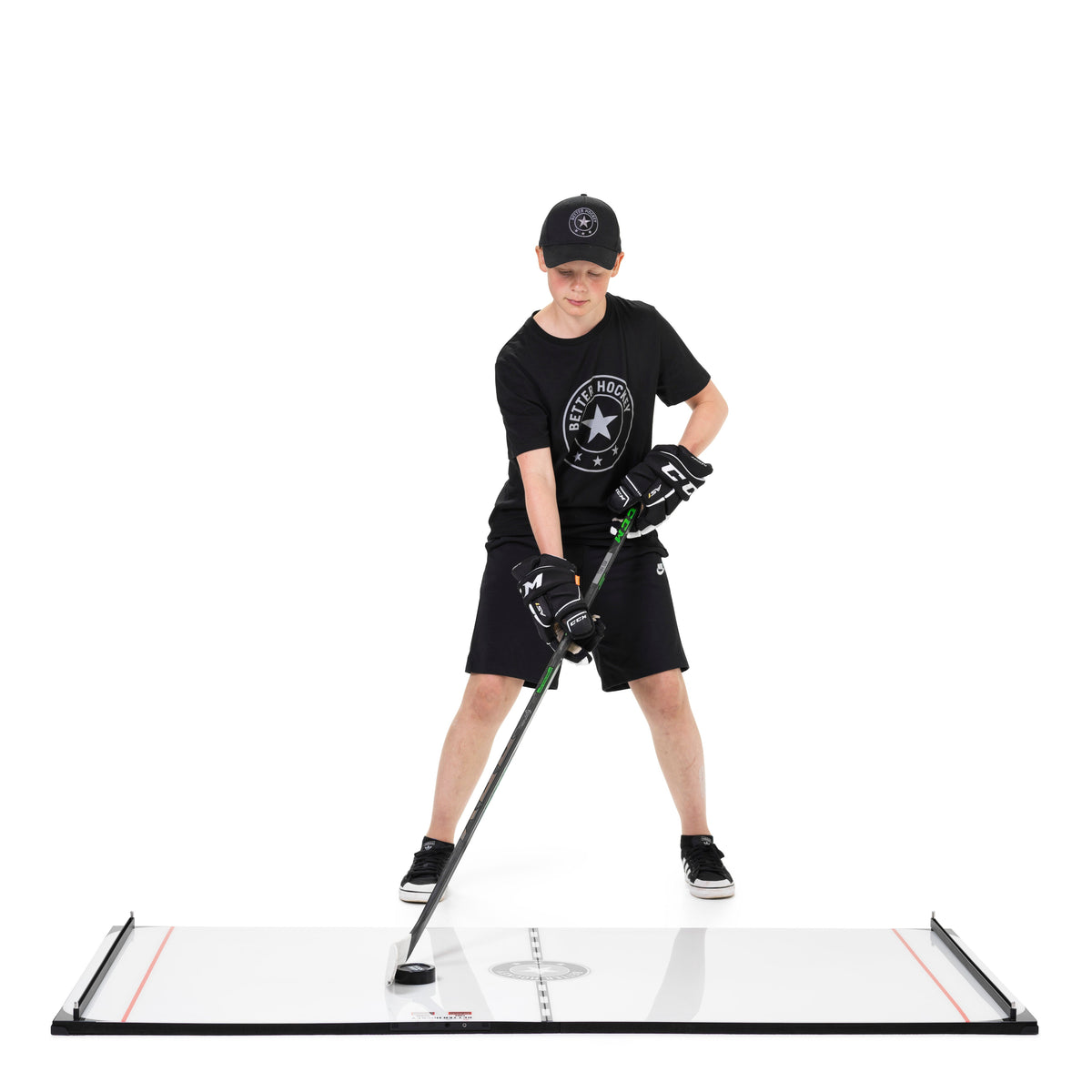Young hockey player stickhandling on the Game Changer board outdoors with a hockey goal in the background