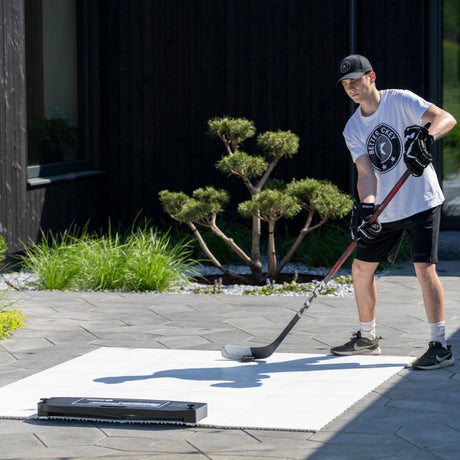 Hockey player training with a passing rebounder kit in a backyard outdoor setting