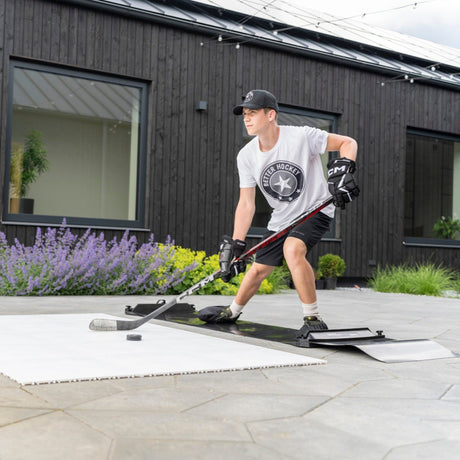Hockey player performing off-ice training on a slide board in a backyard setting