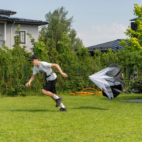 Hockey player sprinting outdoors with a speed chute attached, building explosive first-step acceleration
