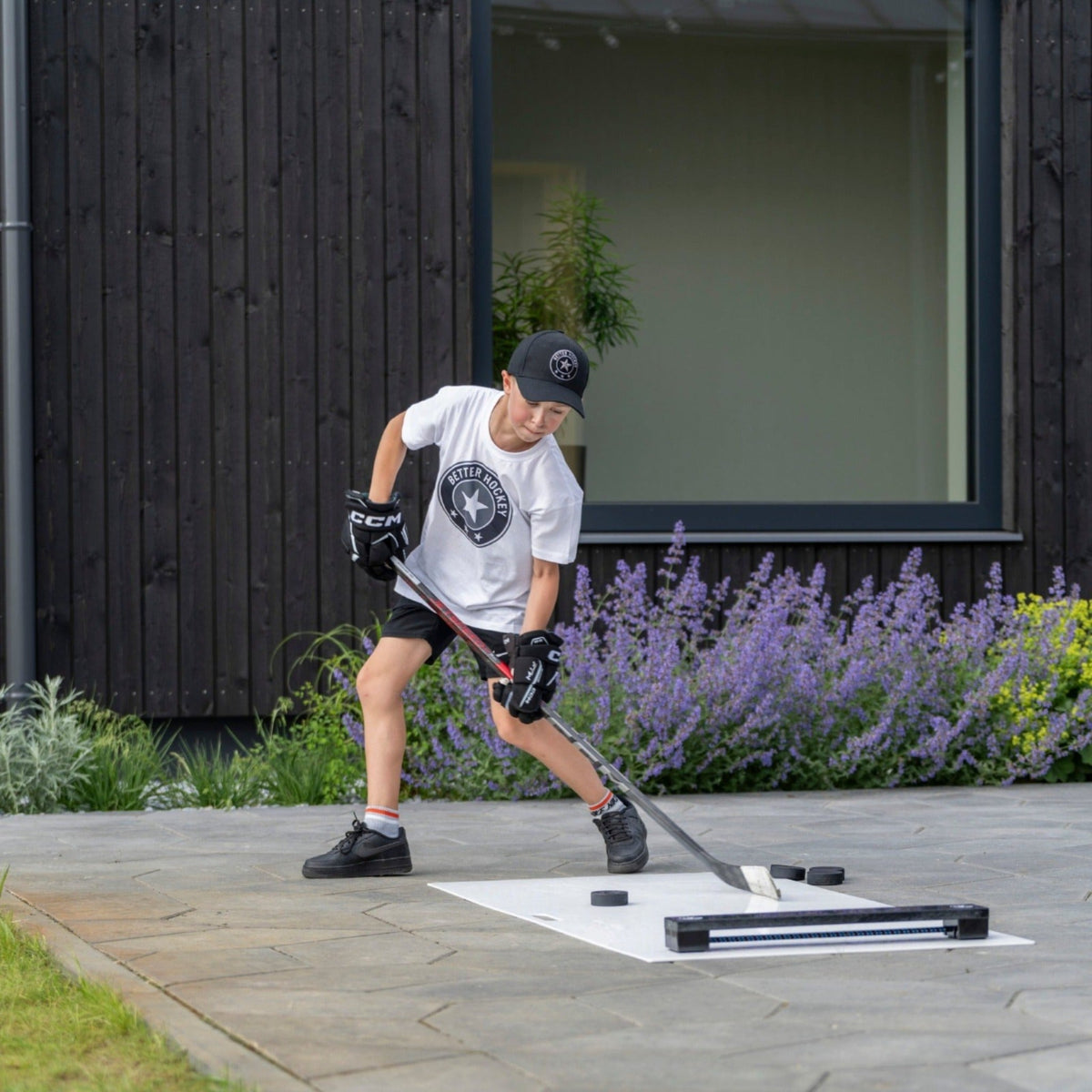 Young hockey player using a rebounder for passing drills outdoors in a backyard setting