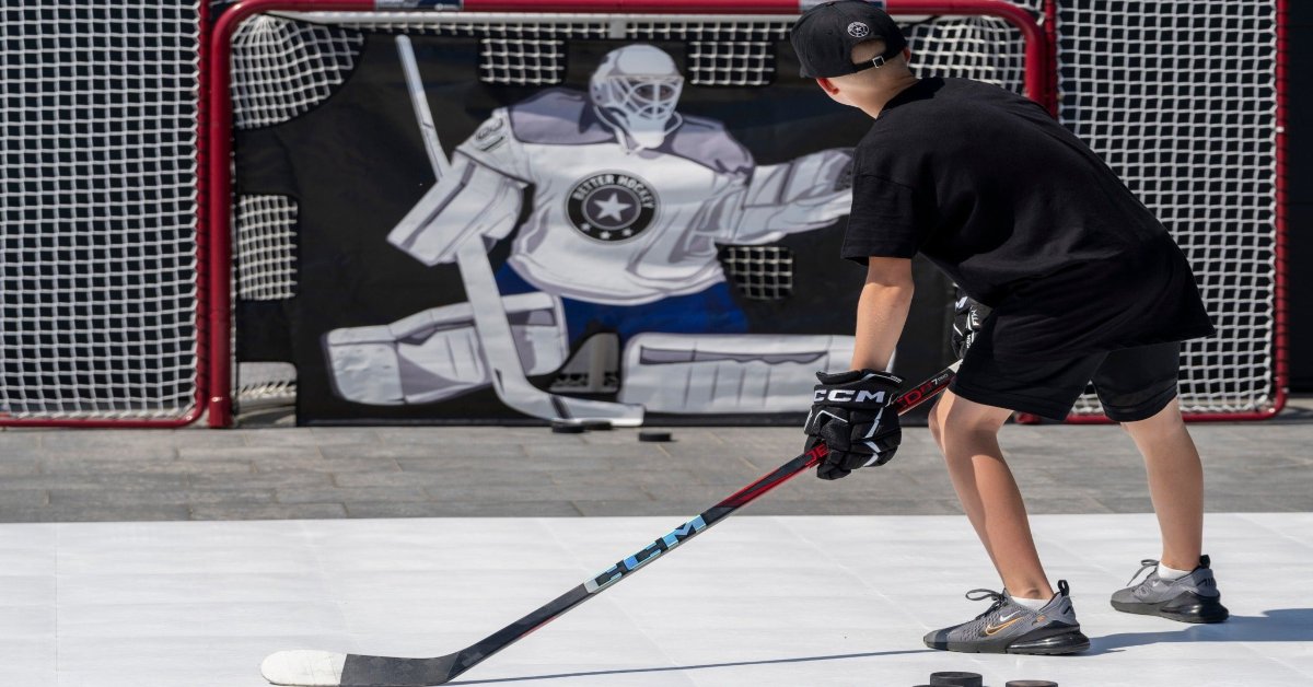 Young hockey player practicing breakaway moves on training tiles with a pro goalie shooter tutor target in the net