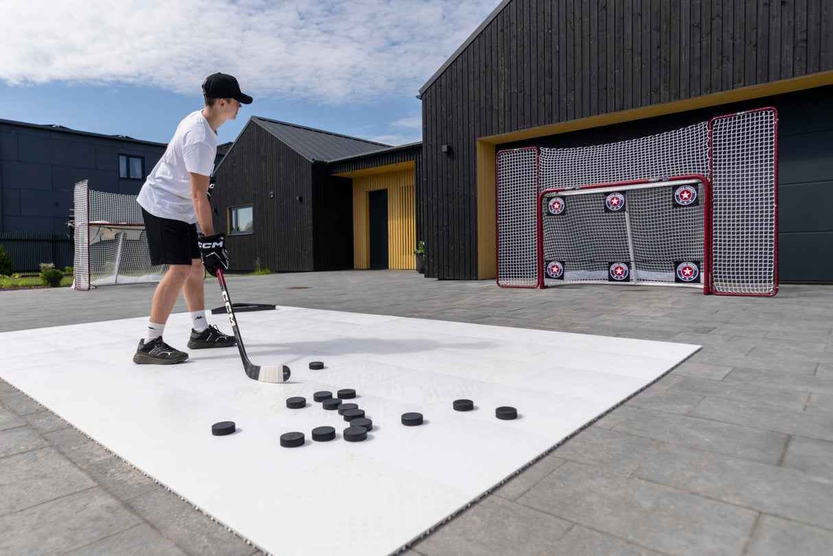 Ung spelare övar hockeyskott med puckar mot Extreme Hockey 4-corner shooting targets i en modern utomhusmiljö.