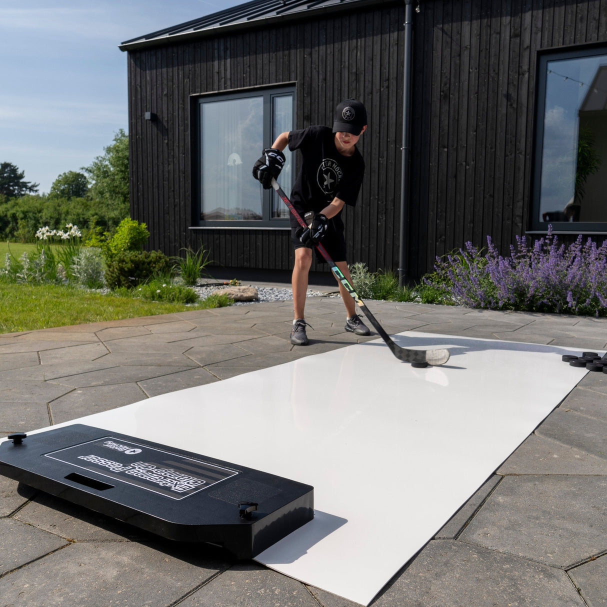 Ungdom spelar hockey med Extreme Hockey Passing Kit Pro XL på skottplatta utomhus, fokuserar på skott och stickhandling.